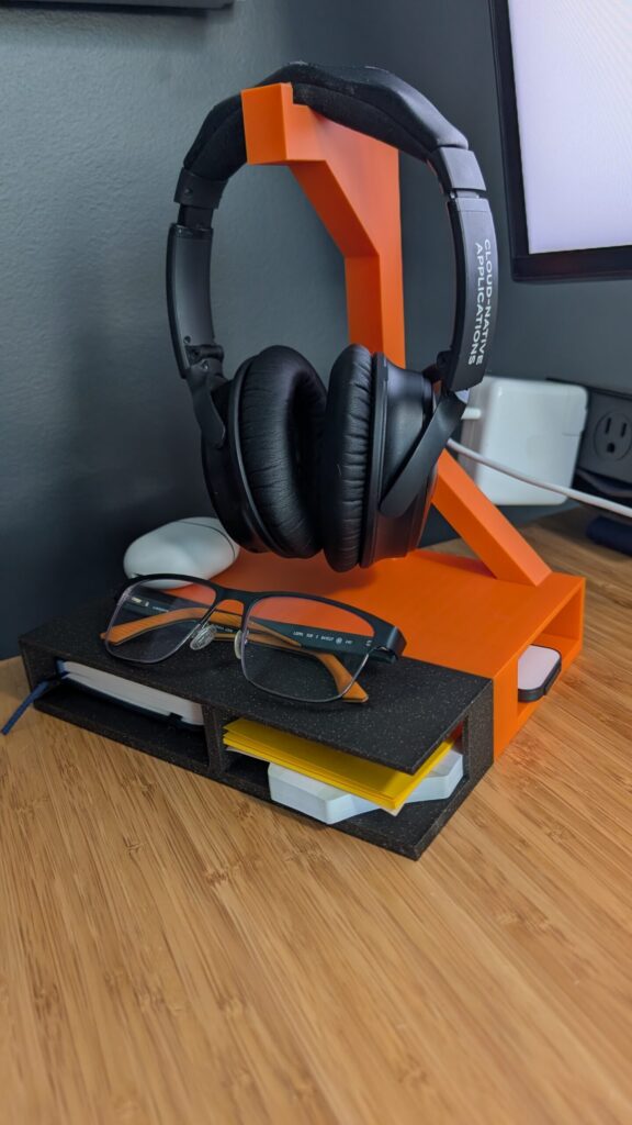 Finished headphone stand in use, holding headphones with glasses and a notebook in the compartments below